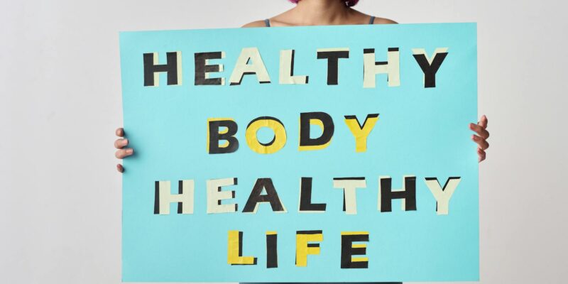 A woman holds a motivational poster advocating a healthy body and life for wellness.