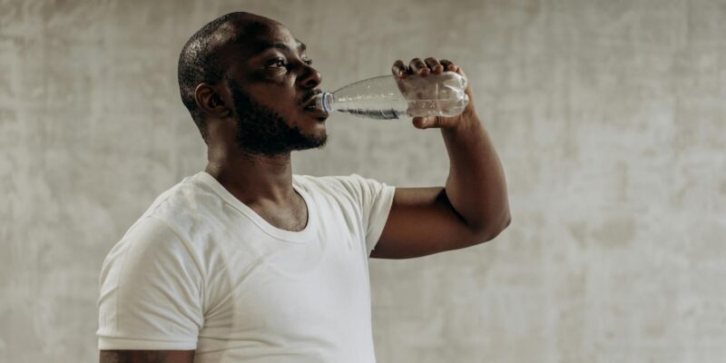 Healthy living concept: Man staying hydrated with water. Indoors, fitness focus.