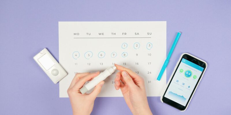 Hands using lancet pen for diabetes monitoring with glucometer and smartphone.