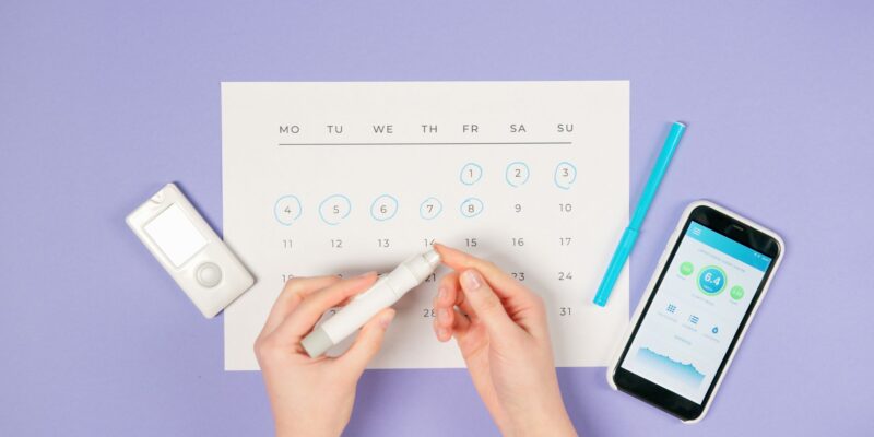 Hands using lancet pen for diabetes monitoring with glucometer and smartphone.
