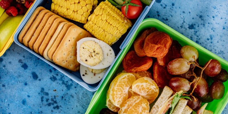 Colorful lunchboxes with fruits, snacks, and vegetables for a balanced meal.